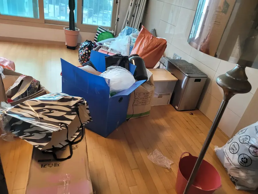 창가 한쪽에 짐과 가구가 모인 이사 전 거실